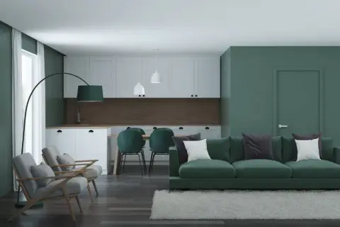 Nowoczesny salon z kuchnią, gdzie króluje **zielony kolor ścian**. Wygodna kanapa, fotele i krzesła tworzą przytulną przestrzeń.