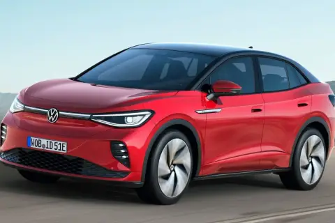 Czerwony VW ID.5 z czarnym dachem sunie po drodze, prezentując nowoczesny design i elektryczną moc.