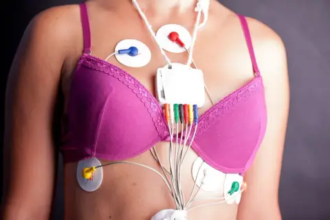Kobieta z przyklejonymi elektrodami i urządzeniem do monitorowania holter ekg.