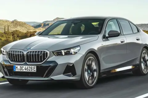 Szare BMW 540d jedzie po drodze na tle górskiego krajobrazu.