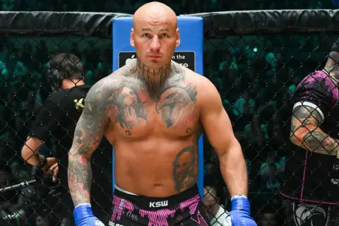 Artur Szpilka w ringu KSW, z tatuażami na klatce piersiowej i rękach.