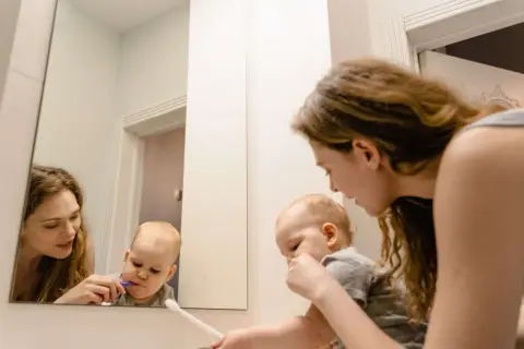 Mama pomaga dziecku myć zęby. Maluch ma lekki odruch wymiotny przy myciu zębów, ale mama go uspokaja.