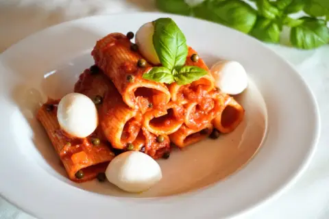 Rigatoni z aromatycznym, czerwonym pesto, kulkami mozzarelli i świeżą bazylią. Pyszne danie, które zachwyca smakiem.