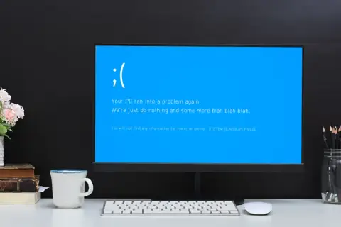 Smutna buźka na niebieskim ekranie komputera. "Your PC ran into a problem again." - klasyczny bluescreen.