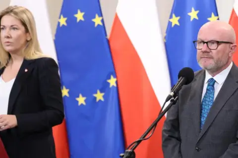 Kobieta i mężczyzna przed mikrofonami na tle flag Polski i UE. Czy ustawa o "teście na polaka" ma szansę przejść przez sejm w marcu?