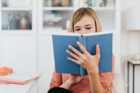 Dziewczynka pochłonięta lekturą, która wywołuje dreszczowiec. Jej oczy błyszczą, gdy śledzi kolejne zwroty akcji.