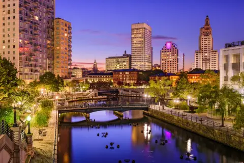 Wieczorny widok na Providence, stolicę najmniejszego stanu USA, Rhode Island. Rzeka otoczona budynkami i zielenią.