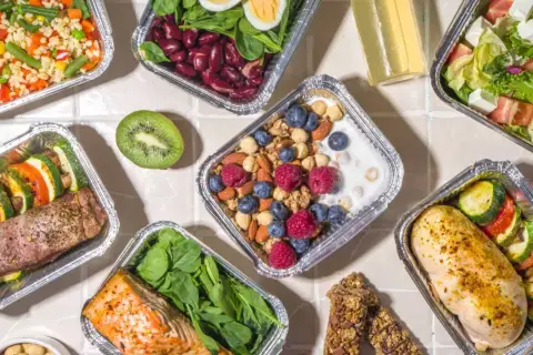 Różnorodne posiłki w pudełkach: łosoś, kurczak, sałatka, owsianka z owocami. Sprawdź, jakie są dieta pudełkowa koszty i wybierz zdrowy catering!