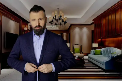 Mężczyzna w garniturze zapina marynarkę w eleganckim salonie.