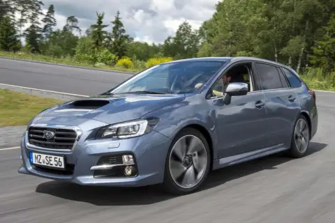 Szary Subaru Levorg na zakręcie drogi, otoczony zielenią.