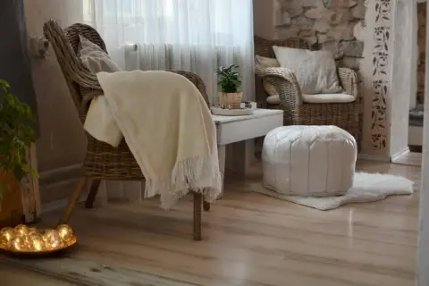 Gemütliche **hygge einrichtung**: Korbstühle, ein weicher Überwurf und ein weißer Pouf laden zum Entspannen ein.