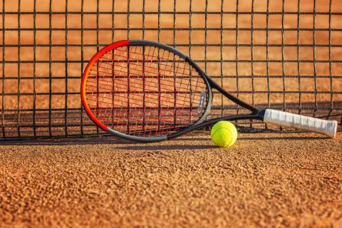 Rakieta tenisowa Wilson Clash i piłka leżą na korcie, gotowe do gry.