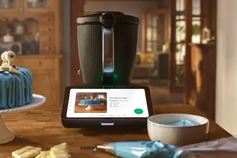 Niebieski tort z oczami na patyczkach obok Thermomixa wyświetlającego przepis. Zastanawiasz się, ile kosztuje abonament Cookidoo?