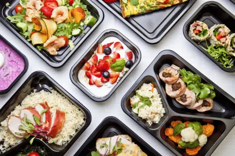 Różnorodne dania z cateringu dietetycznego Augustów: sałatka z krewetkami, jogurt z owocami, ryż z kurczakiem, warzywa i mięso.