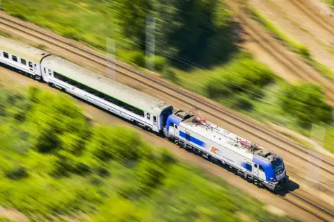 Pociąg PKP Intercity pędzi przez zielone krajobrazy. Chcesz wiedzieć, jak dokupić rezerwację miejsca do kupionego już biletu?