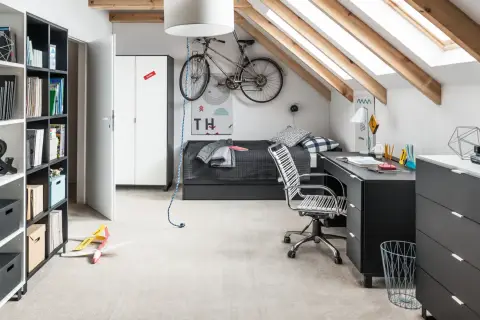 Pokój ze skosem młodzieżowy z rowerem pod sufitem, łóżkiem, biurkiem i regałem.