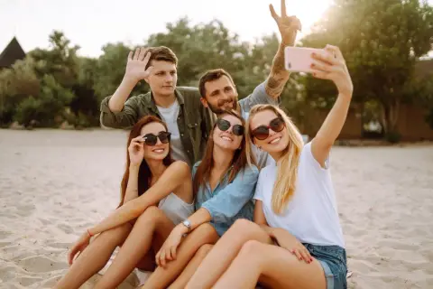 Grupa przyjaciół robi selfie na plaży. Zastanawiasz się, jak sprawdzić, czy roaming jest włączony Plus abonament? Sprawdź to przed wyjazdem!