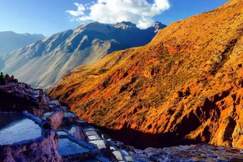 Terrassierte Salinen von Maras, Peru, im warmen Licht der untergehenden Sonne. Die Berge im Hintergrund sind in Schatten getaucht.