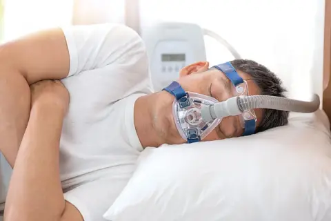 Mann schläft mit CPAP-Maske, um Atemaussetzer am Tag zu behandeln.