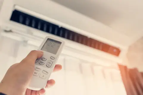 Mano ajustando el control remoto del aire acondicionado para mantener la temperatura ideal. Control de calefacción y refrigeración.