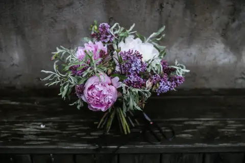 En bukett med rosa pioner, vita pioner och lila syren. Vackra snittblommor sorter som ser ut att vara nyss plockade.