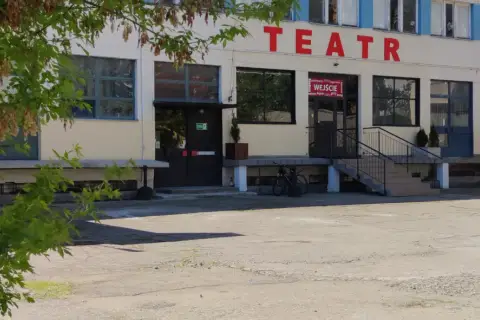 Teatr Druga Strefa. Budynek z czerwonym napisem "TEATR" na fasadzie, wejście z wielojęzycznym napisem "WEJŚCIE".