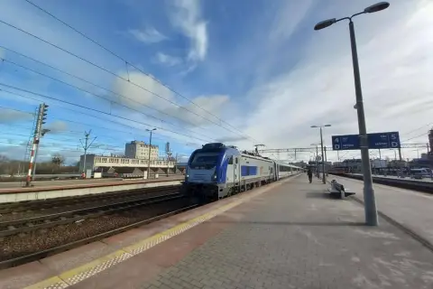 Pociąg na stacji, idealny środek transportu, by dowiedzieć się, jak dostać się do morza. Słońce i chmury na niebie.
