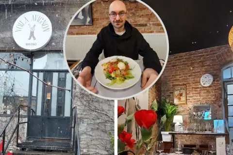 Voila, co znaczy to bistro! Mężczyzna z okularami prezentuje sałatkę w przytulnym wnętrzu z ceglanymi ścianami i stylowymi lampami.