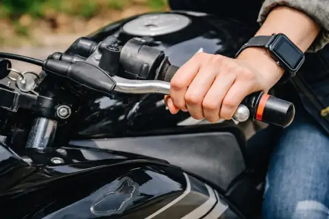Mano sujetando el manillar de una moto negra, lista para arrancar. Aprender a no picar embrague es clave para una conducción suave.