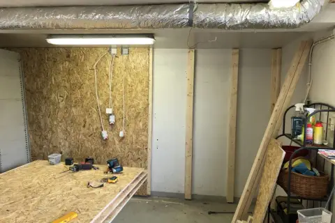 Här ligger skivor av OSB redo att måla. Verktyg och byggmaterial finns på plats för projektet.