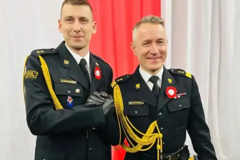 Dwóch mężczyzn w galowych mundurach, z bogatym **uposażeniem**, ściska sobie dłonie.