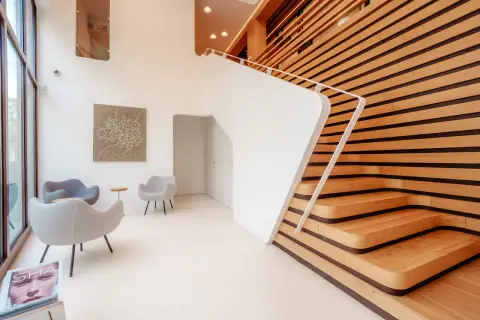 Nowoczesne wnętrze z białymi schodami i drewnianą ścianą. Fotograf architektury uchwycił minimalistyczny design i grę światła.
