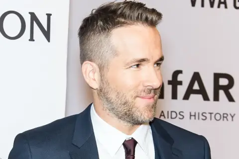 Ryan Reynolds luce un corte de pelo moderno con degradado hombre, barba cuidada y traje oscuro.