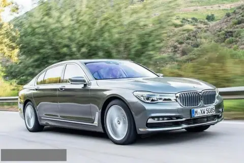 Eleganckie BMW 730d sunie po krętej drodze wśród zieleni.