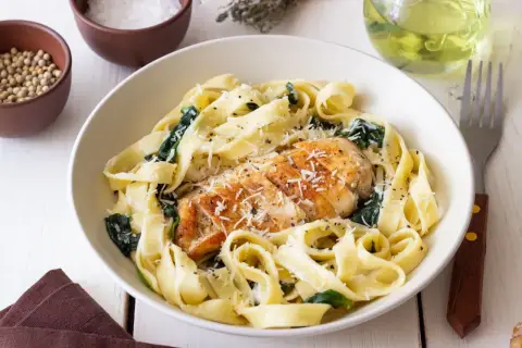 Szybki makaron z kurczakiem i szpinakiem, posypany parmezanem. Idealny na szybki obiad.