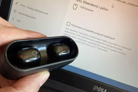 Słuchawki bezprzewodowe w etui, gotowe do połączenia z wieżą. Na ekranie komputera widać ustawienia urządzeń USB.