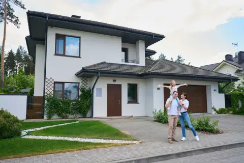 Szczęśliwa rodzina przed nowoczesnym domem. Czy to odzwierciedla realny koszt budowy domu?