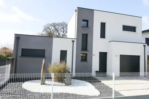 Nowoczesny dom kostka z dwukolorową elewacją, szaro-białą, z dużymi oknami i garażem.