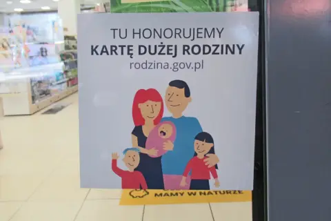 Tu honorujemy kartę dużej rodziny. Uśmiechnięta rodzina z dziećmi na plakacie.