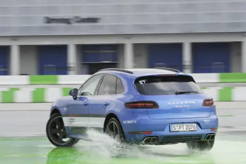 Niebieski Porsche Macan Turbo na mokrym torze Driving Center, rozpryskuje wodę. DSC co to? System stabilizacji toru jazdy.