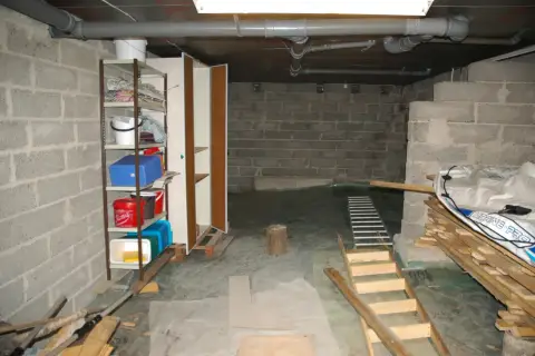 Källare med **mura lecablock**, hyllor med förvaring, rör och en uppblåsbar båt.