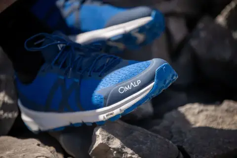 Chaussures de trail bleues CIMALP sur des rochers. Le bon **taille chaussure trail** est essentiel pour l'aventure.