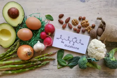 Zdjęcie przedstawia składniki odżywcze, które mogą wspierać produkcję glutationu: awokado, jajka, orzechy, brokuły, kalafior, szpinak, czosnek, cebulę, szparagi i rzodkiewkę.