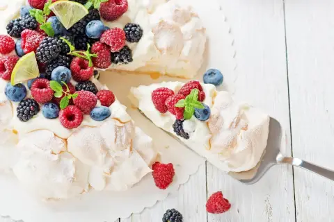 Beza pavlova która zawsze wychodzi, udekorowana świeżymi malinami, borówkami, jeżynami i plasterkami limonki.