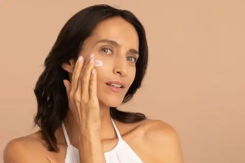 Une femme applique une crème hydratante pour lutter contre la peau sèche.
