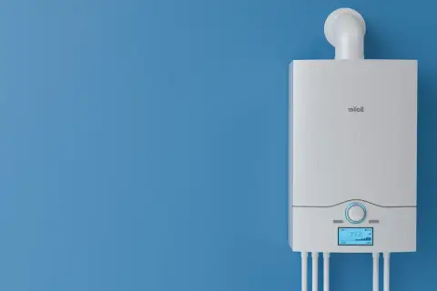 Nowy, biały piec gazowy na niebieskiej ścianie. Dowiedz się, jak wyłączyć piec gazowy na lato, aby zaoszczędzić energię.
