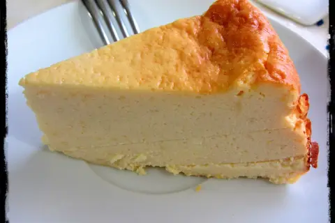 Una rebanada de tarta de queso Philadelphia, con su superficie dorada y cremosa textura, lista para ser disfrutada.