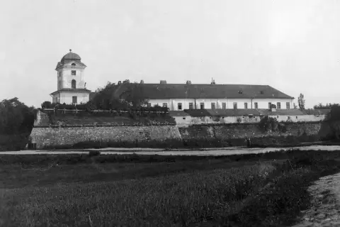 Zamek w Rzeszowie z wieżą i długim budynkiem, otoczony kamiennym murem.