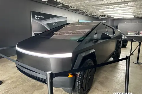 Futurystyczny Cybertruck w matowej czerni, z charakterystycznym pasem LED z przodu, prezentowany na wystawie.