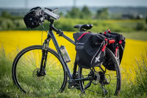 Rower z sakwami Extrawheel gotowy na wyprawę. Jakie sakwy rowerowe wybrać na długą trasę? Te czarne, wodoodporne, z czerwonymi akcentami, wyglądają na solidne.